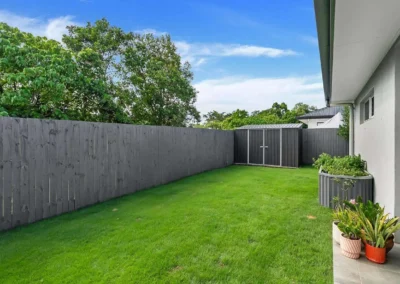 An enhanced backyard lawn photo with a perfect blue sky, edited for professional real estate listing use.